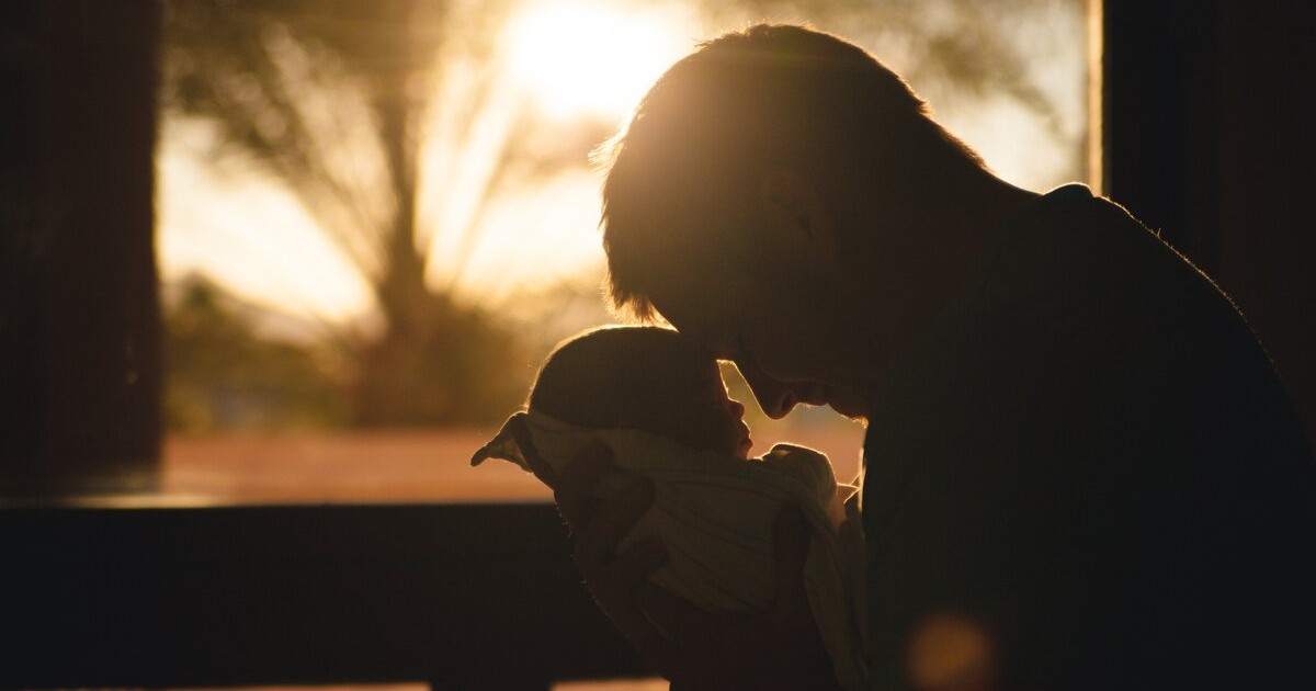 Dad holding his newborn daughter in the sun