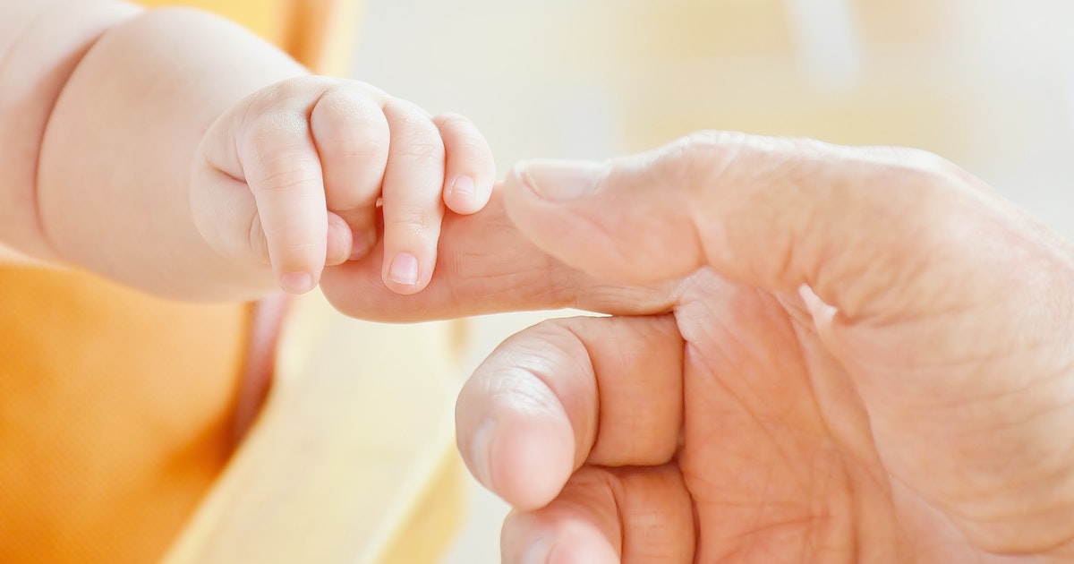 Dad holding a newborn son's hand